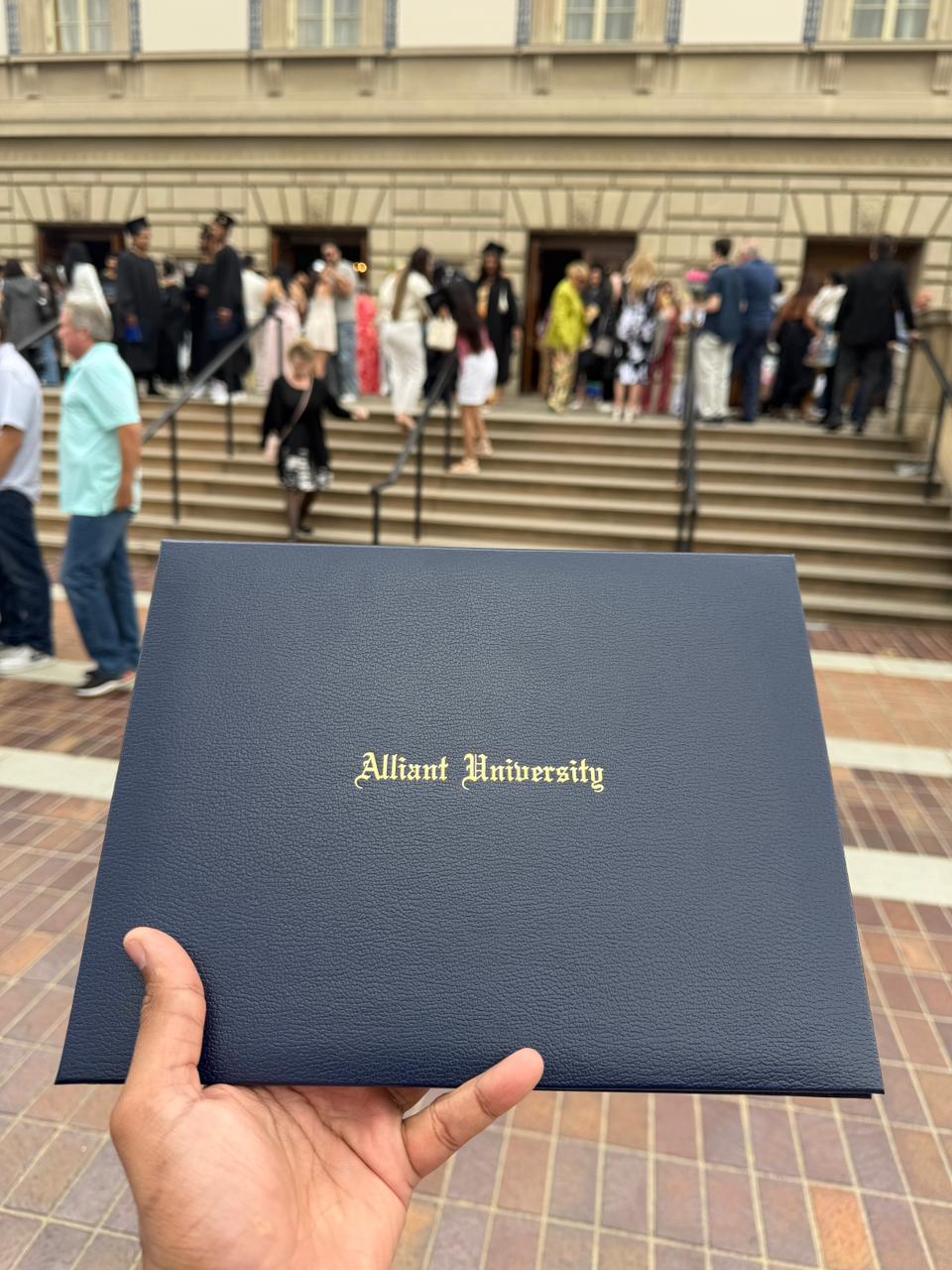 Aniket Shetty holding his Alliant University diploma